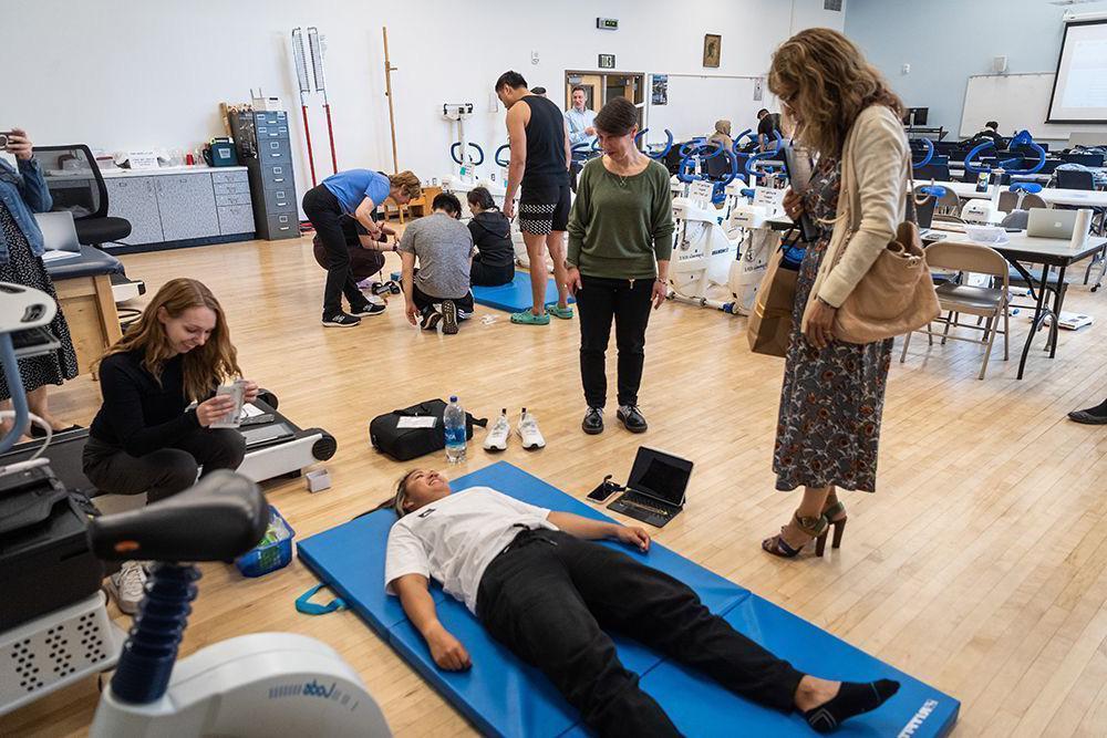 总统在健康与人文科学学院参观时看着一名学生躺在瑜伽垫子上.